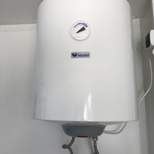 Contentor sanitário com chuveiro, lavatório e sanita.
