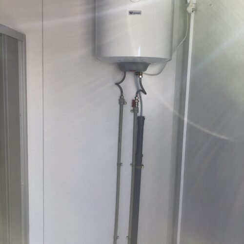 Contentor sanitário com chuveiro, lavatório e sanita.