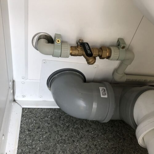 Contentor sanitário com chuveiro, lavatório e sanita.
