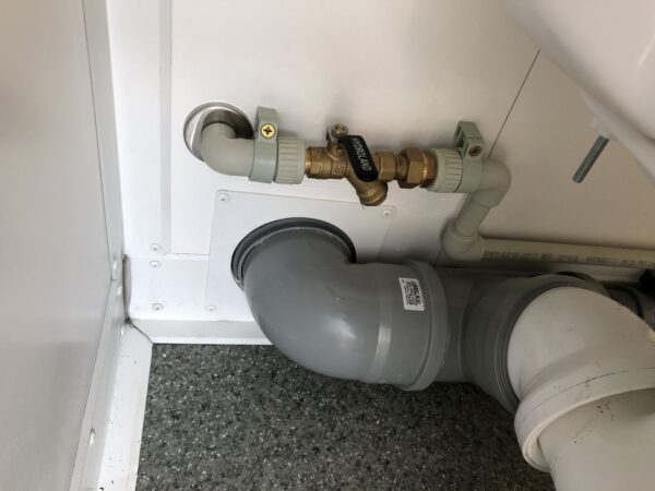 Contentor sanitário com chuveiro, lavatório e sanita.