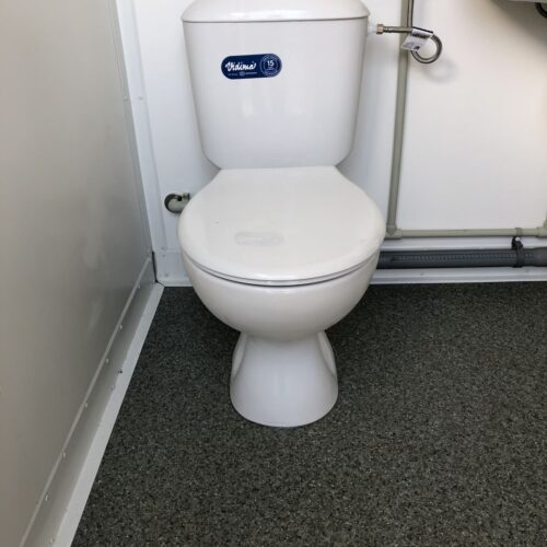 Contentor sanitário com chuveiro, lavatório e sanita.