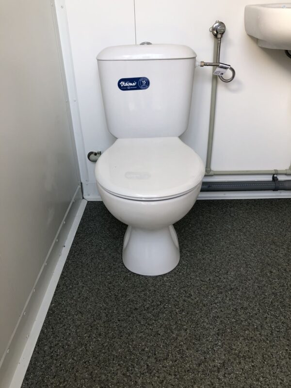 Contentor sanitário com chuveiro, lavatório e sanita.